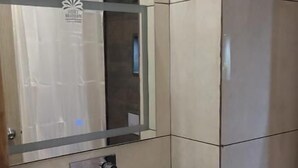 Un baño con un lavamanos blanco, un espejo y una pared con azulejos.