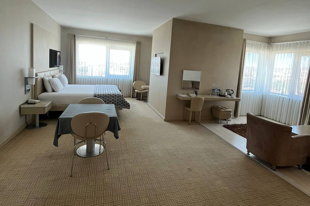 Una habitación de hotel con cama, escritorio, silla, sofá y bañera.