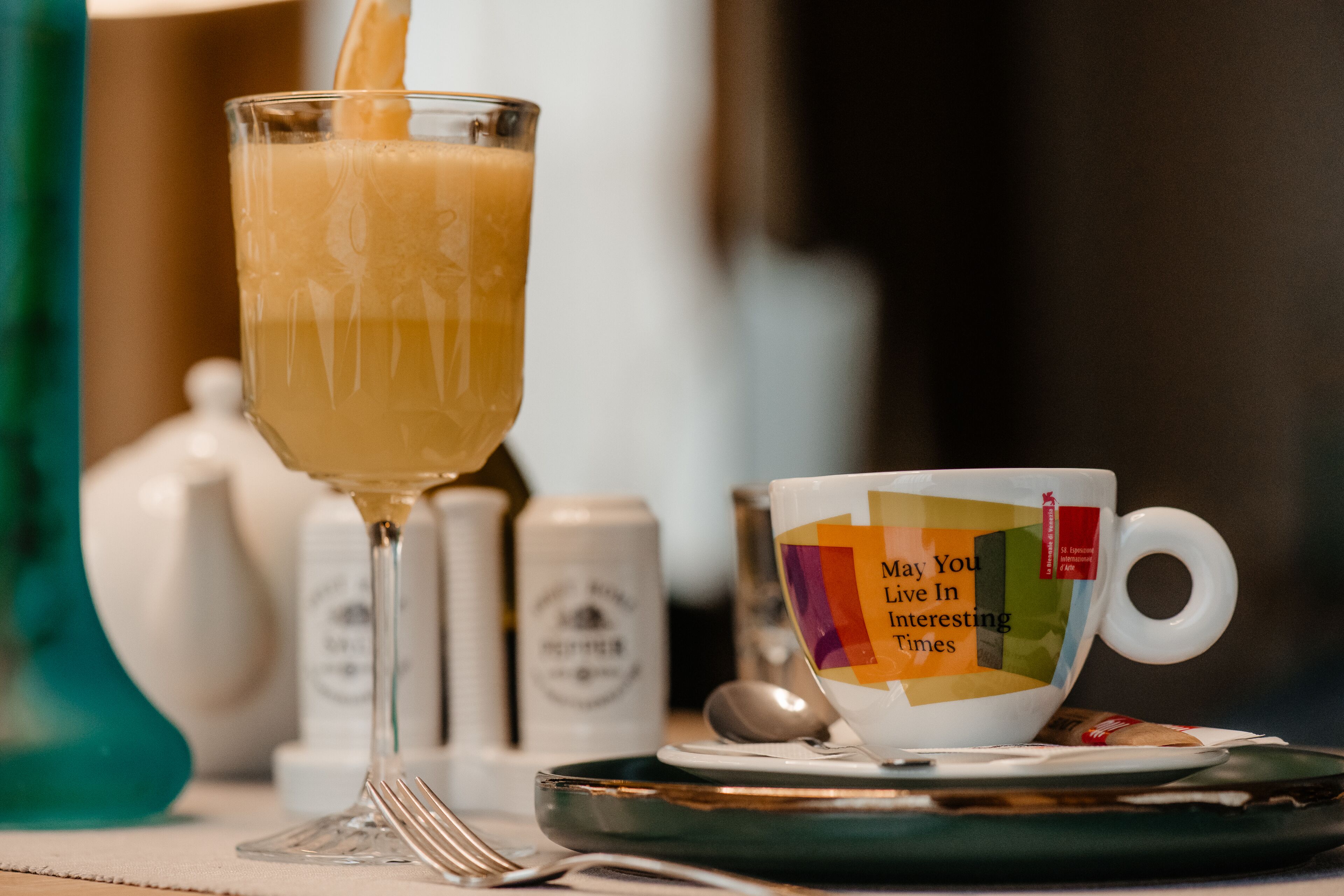 A glass of orange juice being poured into a cup with a colorful design.