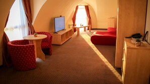 Una habitación acogedora y curvada con televisión, una mesita y muebles rojos.