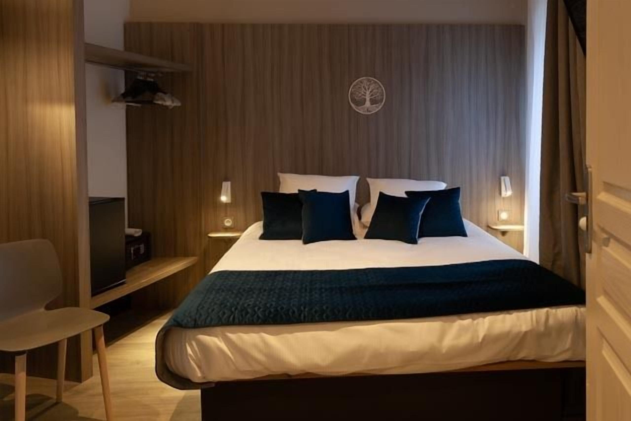 A hotel room with a bed, bedside tables, a desk, and a chair.