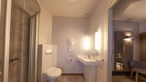 A modern bathroom with a shower, toilet, sink, and mirror. - HNG Hotel Nancy Gare (Nancy)