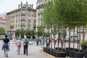 A public square with a row of potted trees, a fountain, and historic buildings in the background. - HNG Hotel Nancy Gare (Nancy)