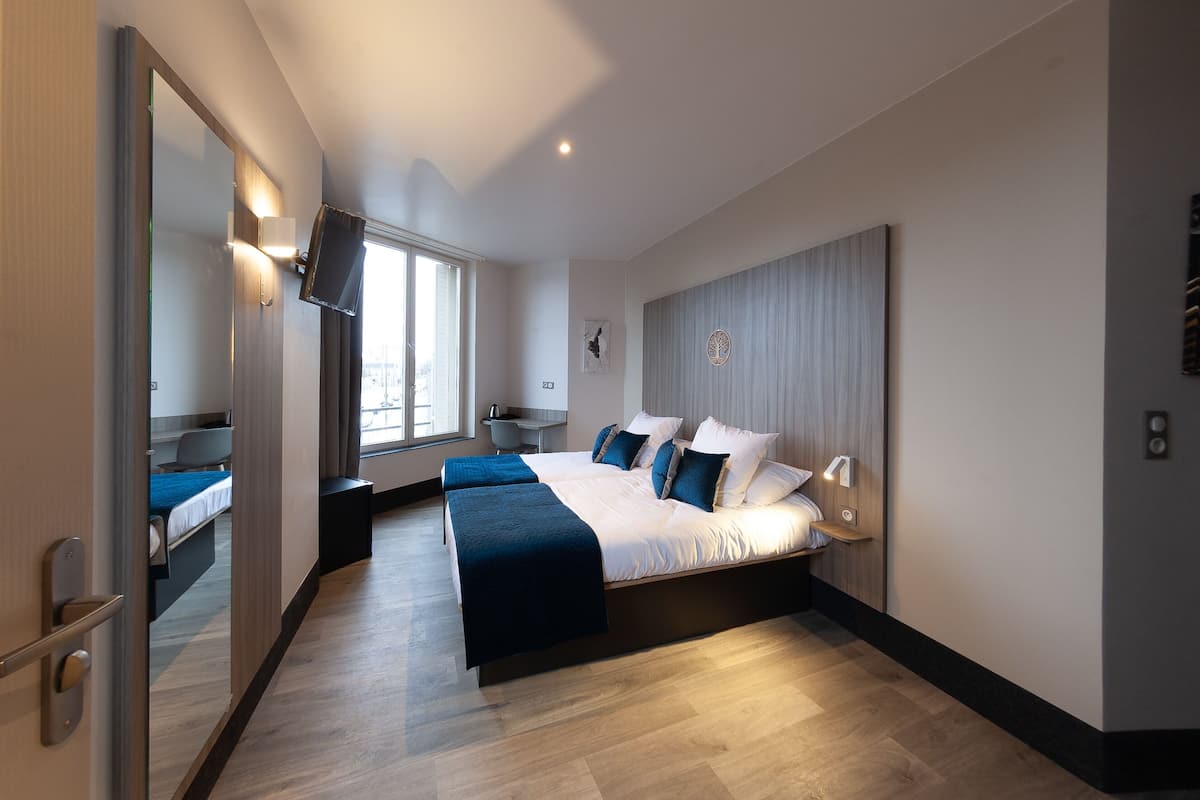A modern hotel room with a large bed, bedside tables, a TV, and a window with a city view.