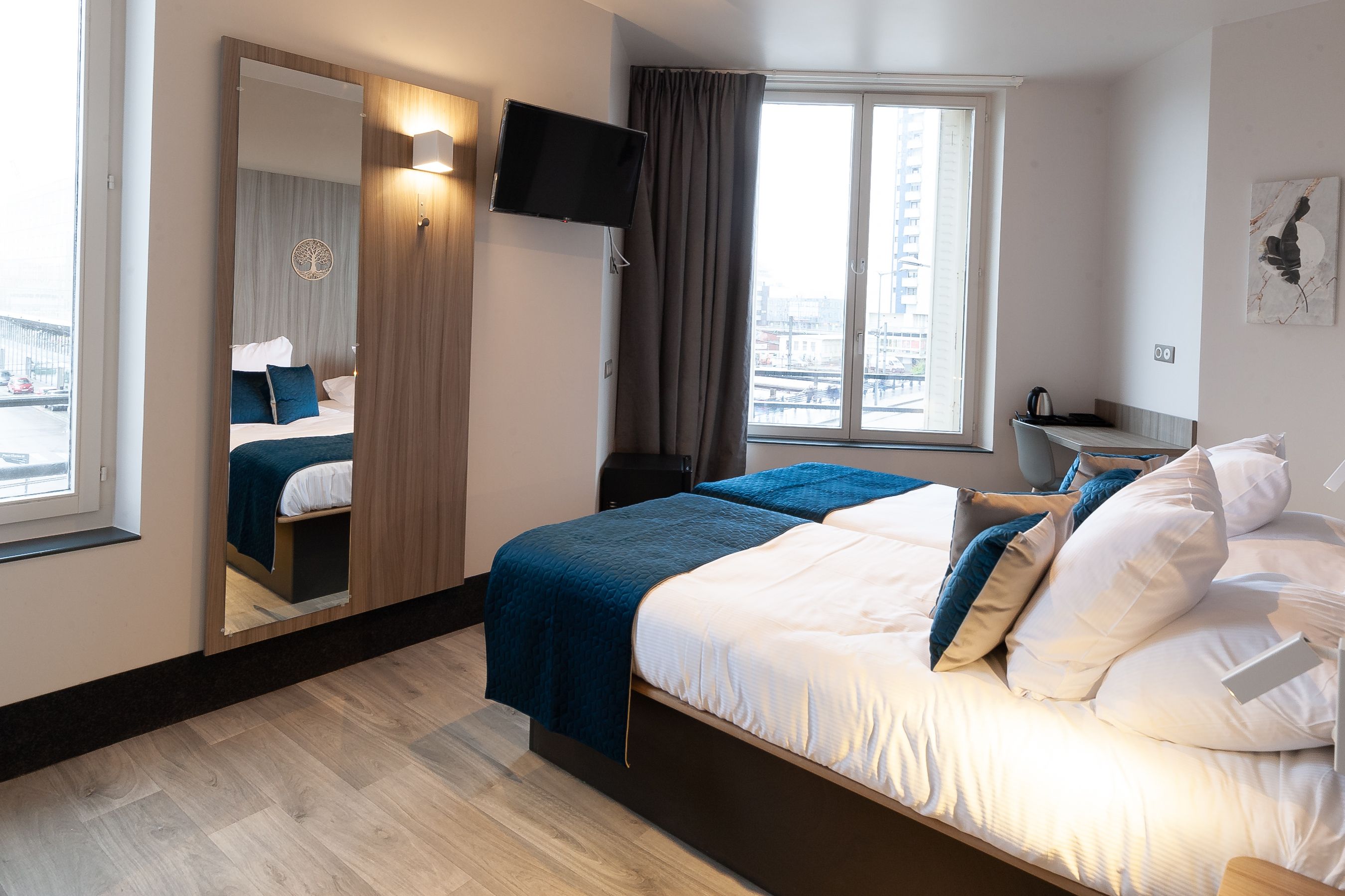 A hotel room with a bed, a TV, a desk, and a view of the city.