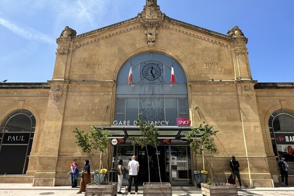 A historic building with a clock, flags, and storefronts including 'GARE D'ENANCY' and 'PAUL'. - HNG Hotel Nancy Gare (Nancy)