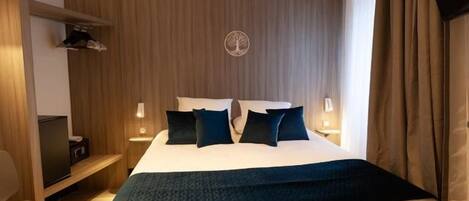 A hotel room with a bed, bedside tables, a desk, and a chair.