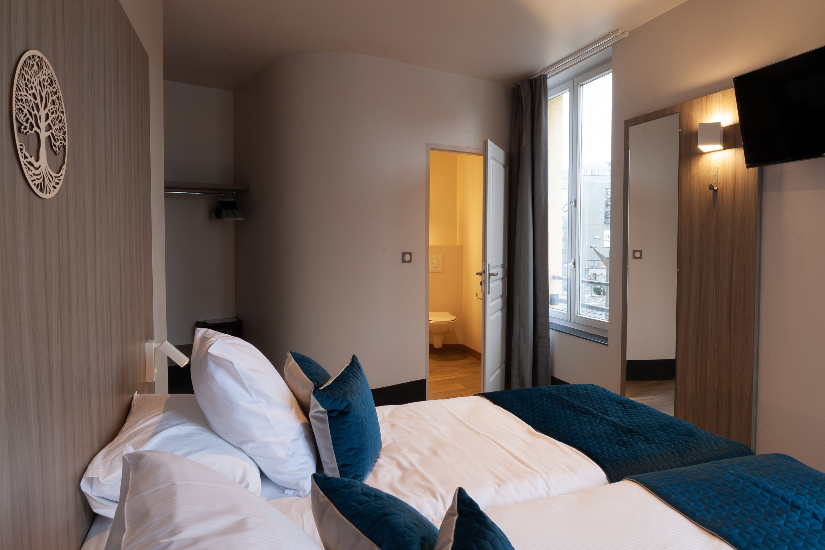 Une chambre d’hôtel moderne, équipée d’un lit, d’une table de chevet, d’un miroir et offrant une vue sur la salle de bain.