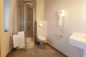 A bathroom with a glass shower enclosure, a toilet, and a sink. - HNG Hotel Nancy Gare (Nancy)
