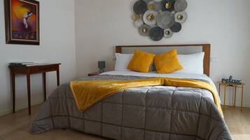 Une chambre à coucher comprenant un lit, une table de chevet, une lampe, un tableau décoratif et une petite table sur laquelle est posé un panneau.