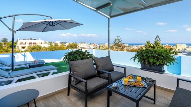 A balcony with a table, chairs, and a potted plant. - Sky High Loft Apartment (Rodos)