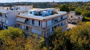 A multi-story residential building with balconies, a flat roof, and a view of a hilly landscape. - Sky High Loft Apartment (Rodos)