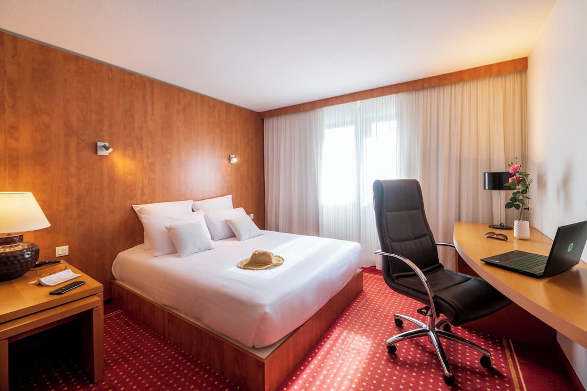 Habitación de hotel con cama, escritorio, silla y una computadora portátil.