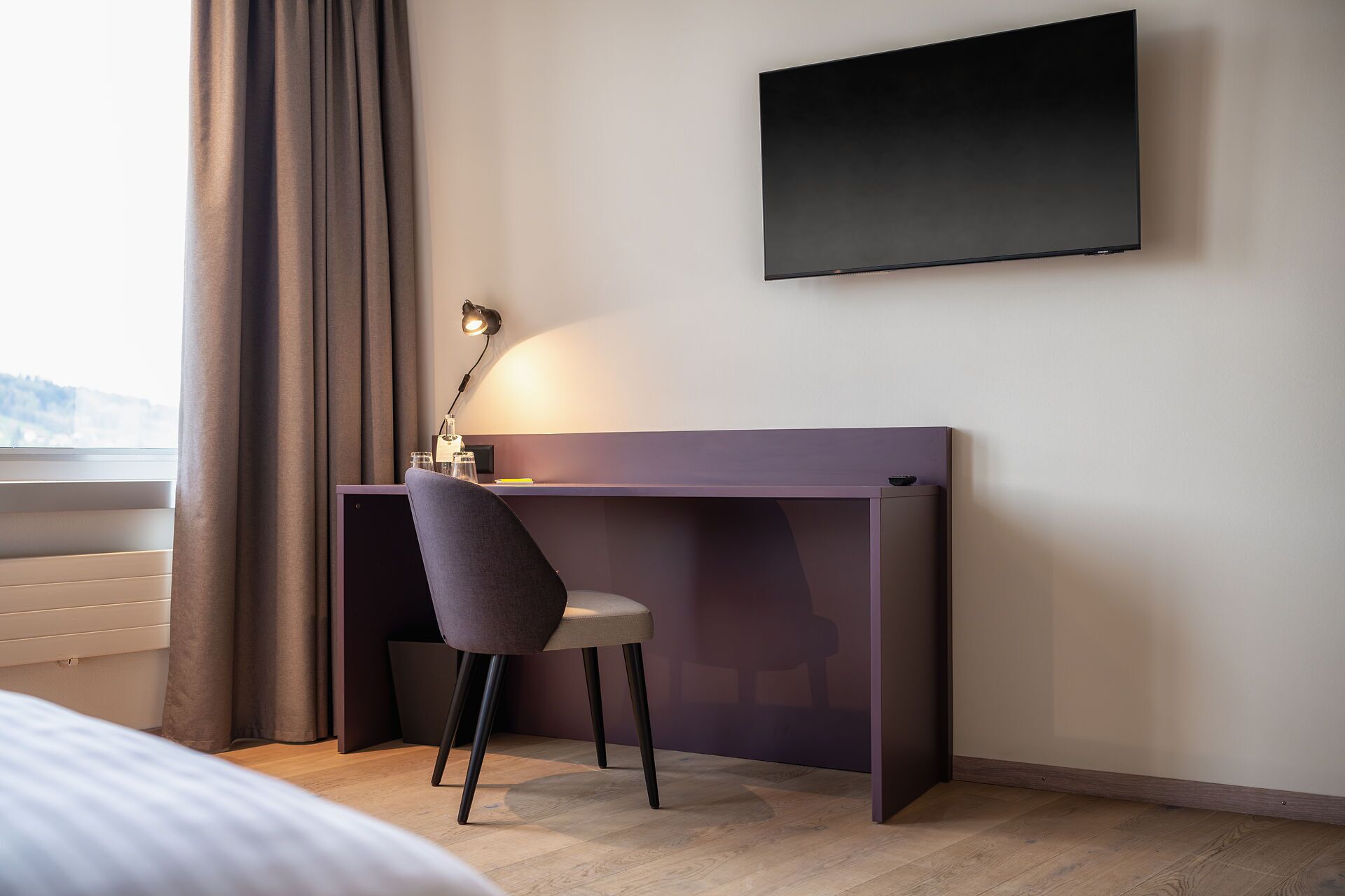 Une chambre moderne équipée d’un bureau, d’une chaise et d’un téléviseur fixé au mur.