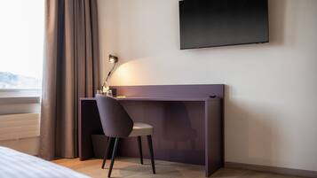 Une chambre moderne équipée d’un bureau, d’une chaise et d’un téléviseur fixé au mur.