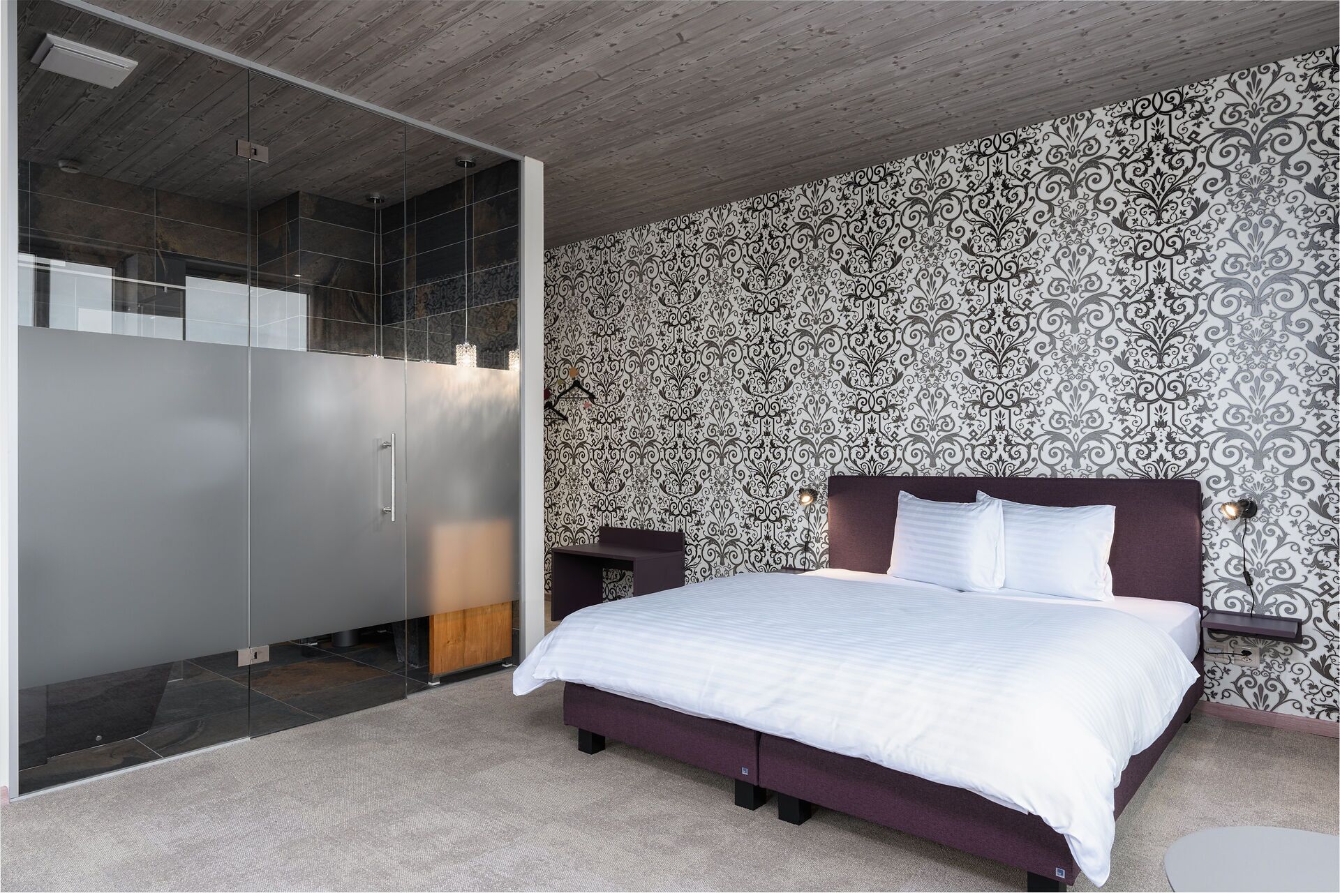 A modern bedroom with a large bed, a wardrobe, and a mirror.