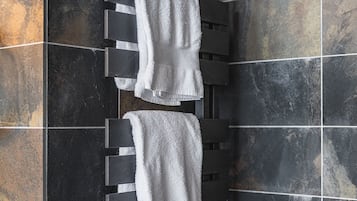 A bathroom with a black towel rack holding two white towels.
