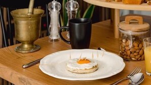 Une table en bois sur laquelle se trouvent une assiette de nourriture, une bouteille, une carafe et un bocal de noix.