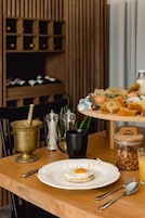Uma mesa de madeira com um prato de comida, uma garrafa, um jarro e um pote de nozes.