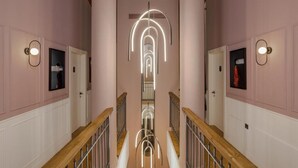 Un couloir avec un luminaire central, des rampes en bois et des portes de part et d’autre.