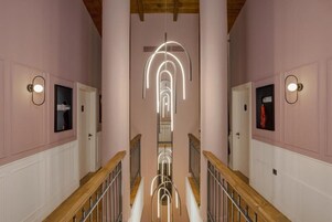 Un pasillo con una instalación de luces en el centro, barandillas de madera y puertas a ambos lados.