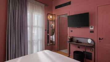 Ein Hotelzimmer mit Bett, Schreibtisch mit Stuhl, Fernseher und Spiegel.