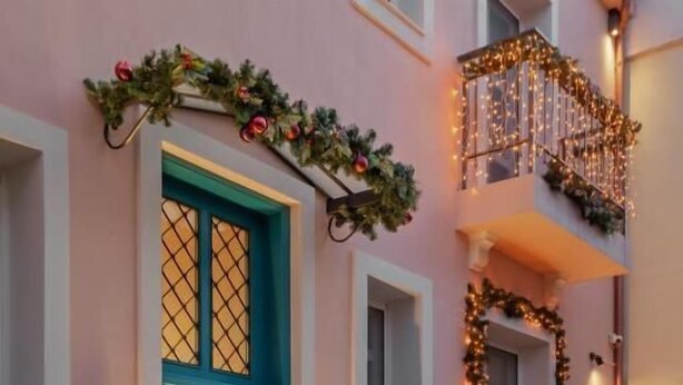 Un bâtiment avec une porte turquoise, des marches en pierre et un balcon décoré de guirlandes lumineuses.