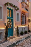 Un edificio con una puerta turquesa, escalones de piedra y un balcón con luces colgantes.