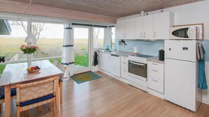 Ett modernt kök med vita skåp, en Bosch-mikrovågsugn och ett stort fönster med utsikt över en gräsklädd åker.