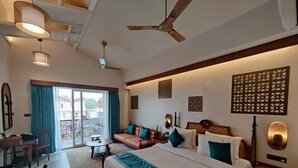 A hotel room with a bed, a sofa, a desk, and a balcony with a view. - Hotel Sonar Bangla Mayapur (Krishnanagar)