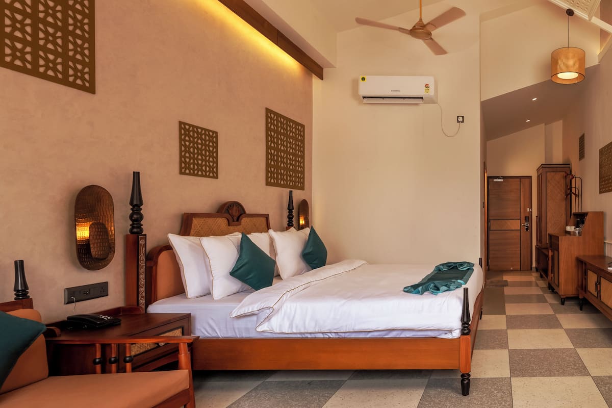 Quarto de hotel com cama, mesa de cabeceira, abajur e ventilador de teto.