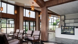 A modern hotel lobby with seating, large windows, and a dessert display. - Hotel Sonar Bangla Mayapur (Krishnanagar)