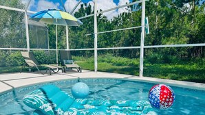 A swimming pool with inflatable loungers and a beach ball.