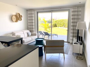 A modern living room with a sofa, a dining table, a coffee table, and a TV stand. - Albufeira Malpique Beach Apartment (Albufeira)