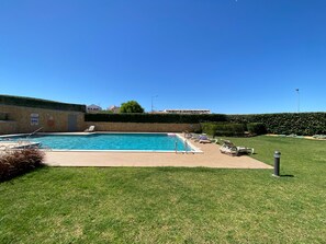 A swimming pool with lounge chairs and a stone wall. - Albufeira Malpique Beach Apartment (Albufeira)