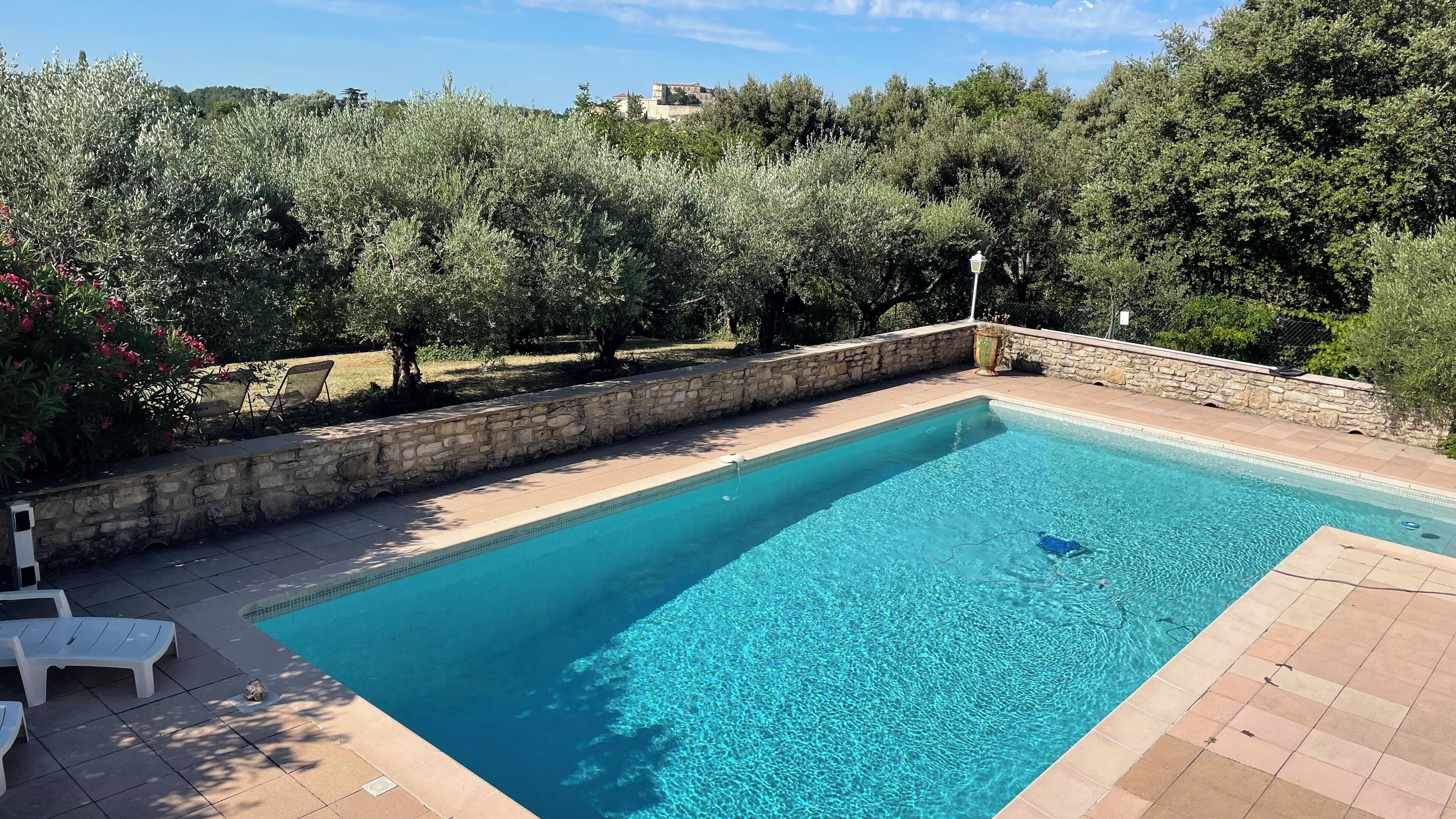 Ein rechteckiger Pool mit klarem, blauem Wasser, umgeben von einer Steinmauer und einem Kiesweg.