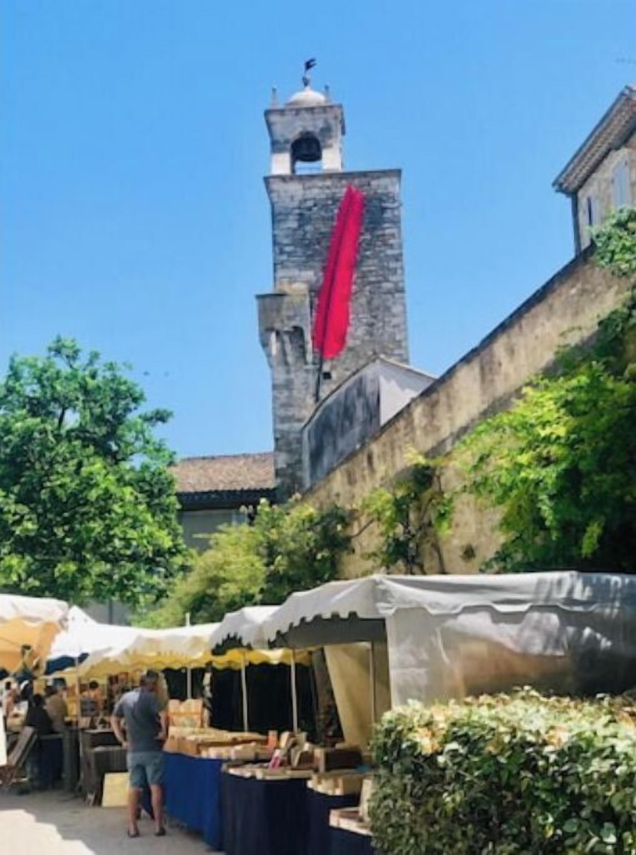 Un edificio histórico con una torre de campanas y un área de mercado con carpas.