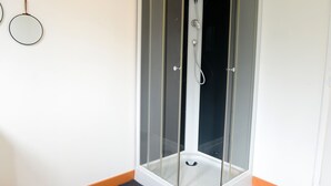 Un'area doccia con pareti in vetro, base bianca e soffione metallico.