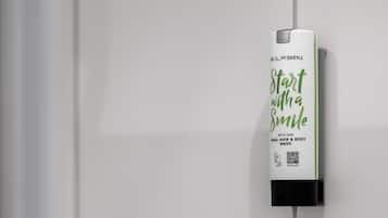 A hand sanitizer dispenser mounted on a white tiled wall.