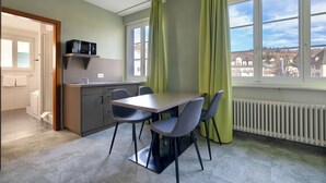 A modern kitchen with a dining area, green curtains, and a view of the city. - flexy.motel Schönenwerd (Schonenwerd)