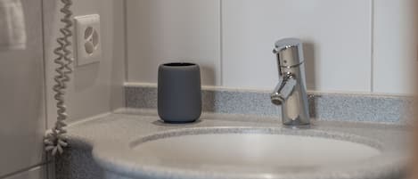 Standaard eenpersoonskamer | Badkamer | Een haardroger, handdoeken, zeep, shampoo