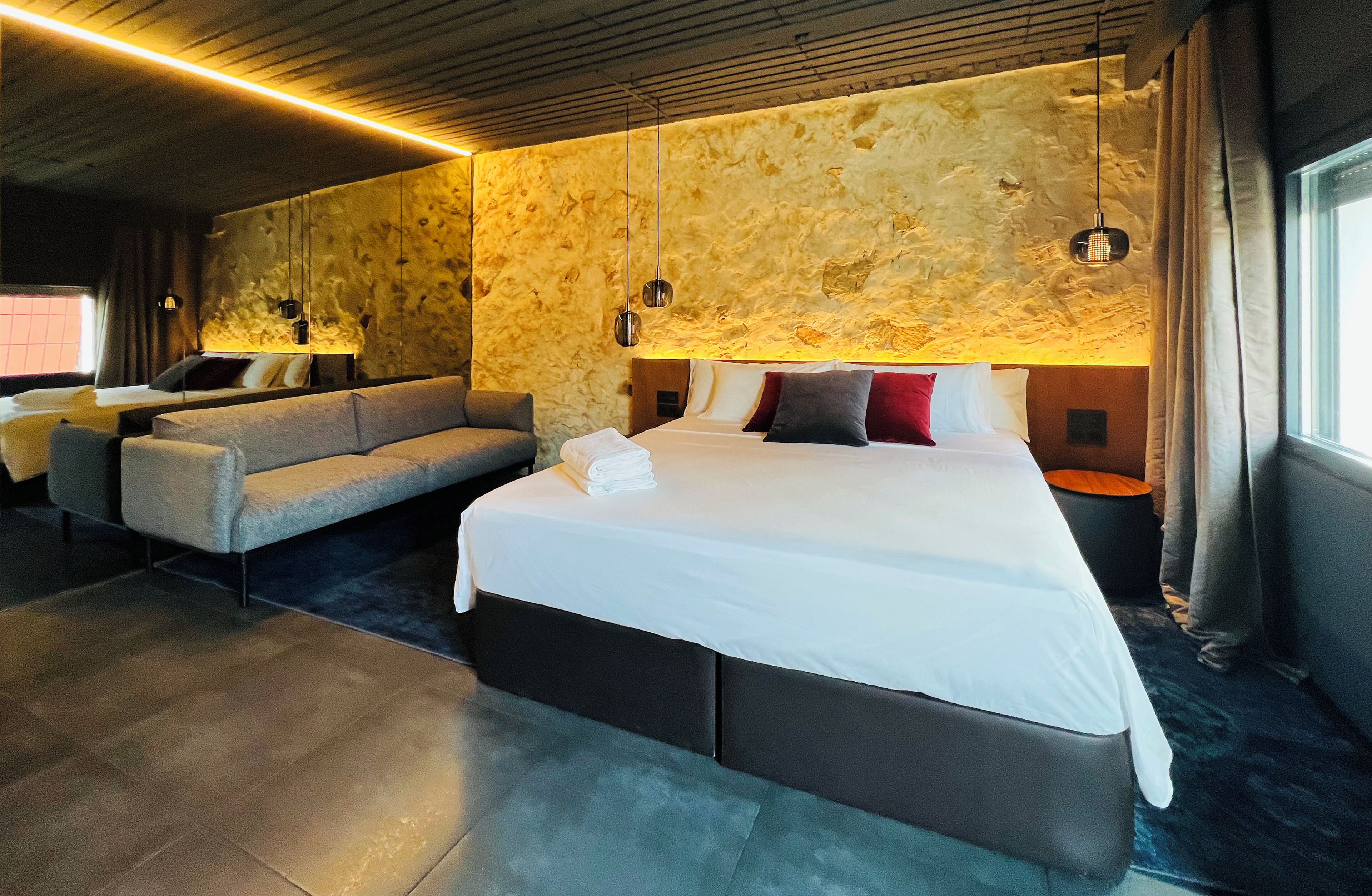 Una habitación de hotel moderna con una cama grande, un sofá y una pequeña mesa.