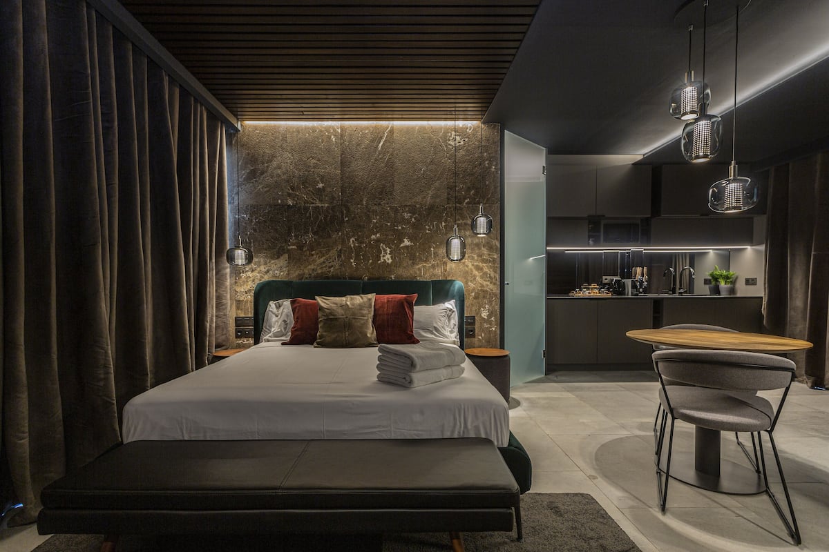 A modern bedroom with a large bed, bedside tables, a desk, and a chair.