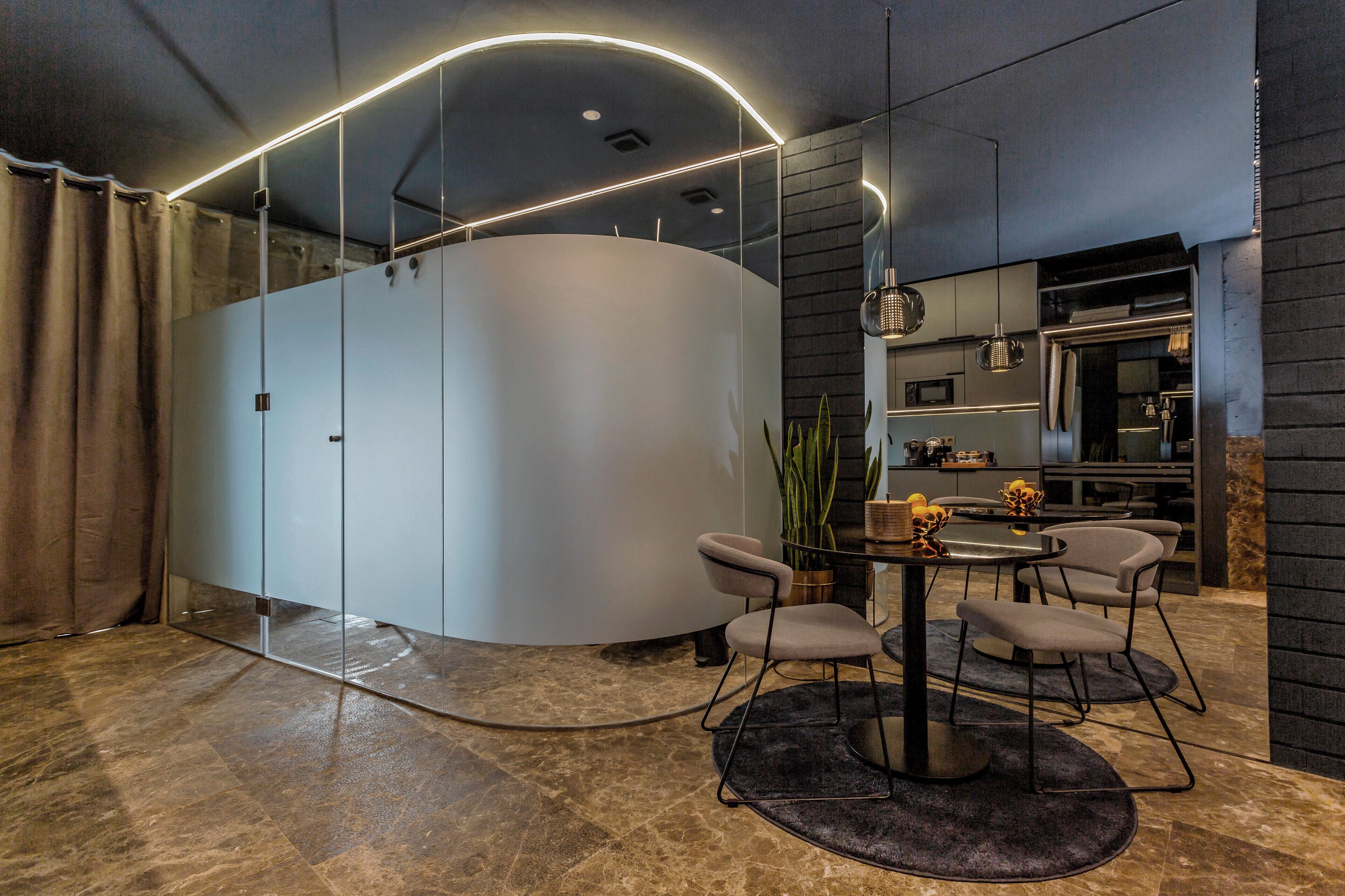 Um interior moderno com uma parede curva, uma mesa de jantar redonda e quatro cadeiras.