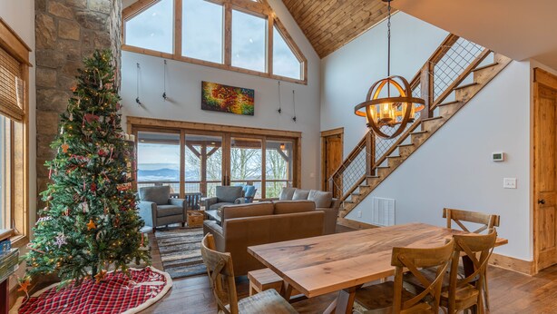 Un vaste espace de vie comprenant une table à manger en bois, un sapin de Noël et un escalier menant à l’étage supérieur.