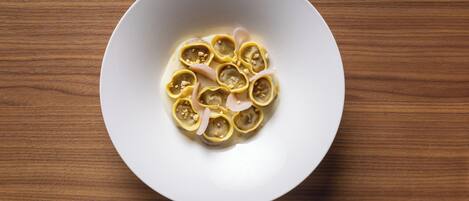 A white bowl containing dumplings on a wooden table.