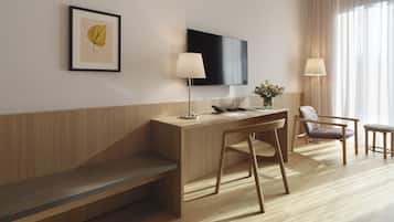 Una habitación de hotel moderna con un escritorio de madera, un televisor de pantalla plana, un banco y dos sillas.