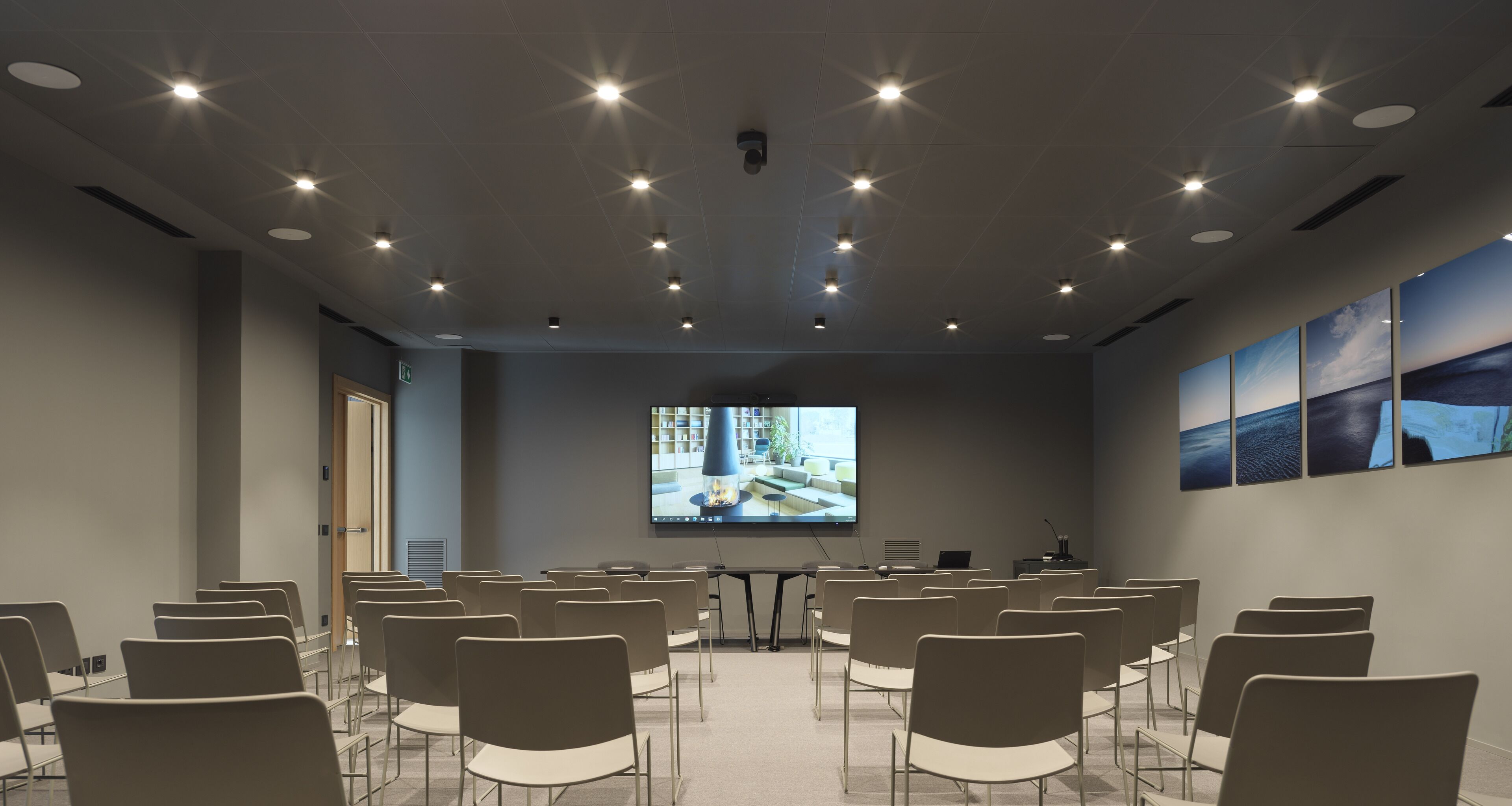 A conference room with rows of chairs, a projection screen, and a table with a laptop.