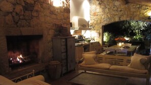 Una sala de estar acogedora con chimenea de piedra, asientos cómodos y una mesa de comedor preparada para dos.