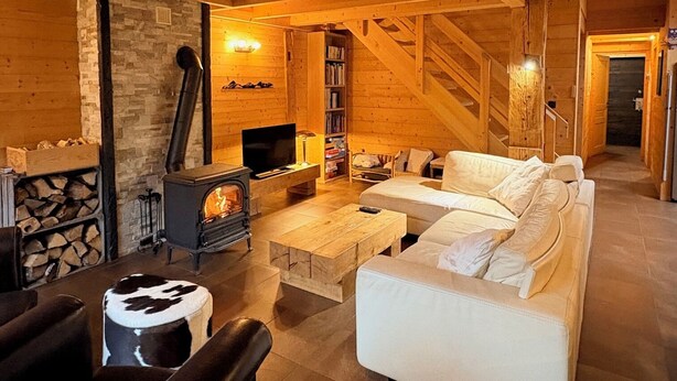 Un acogedor interior de cabaña de madera con chimenea, muebles de madera y una pared de piedra.